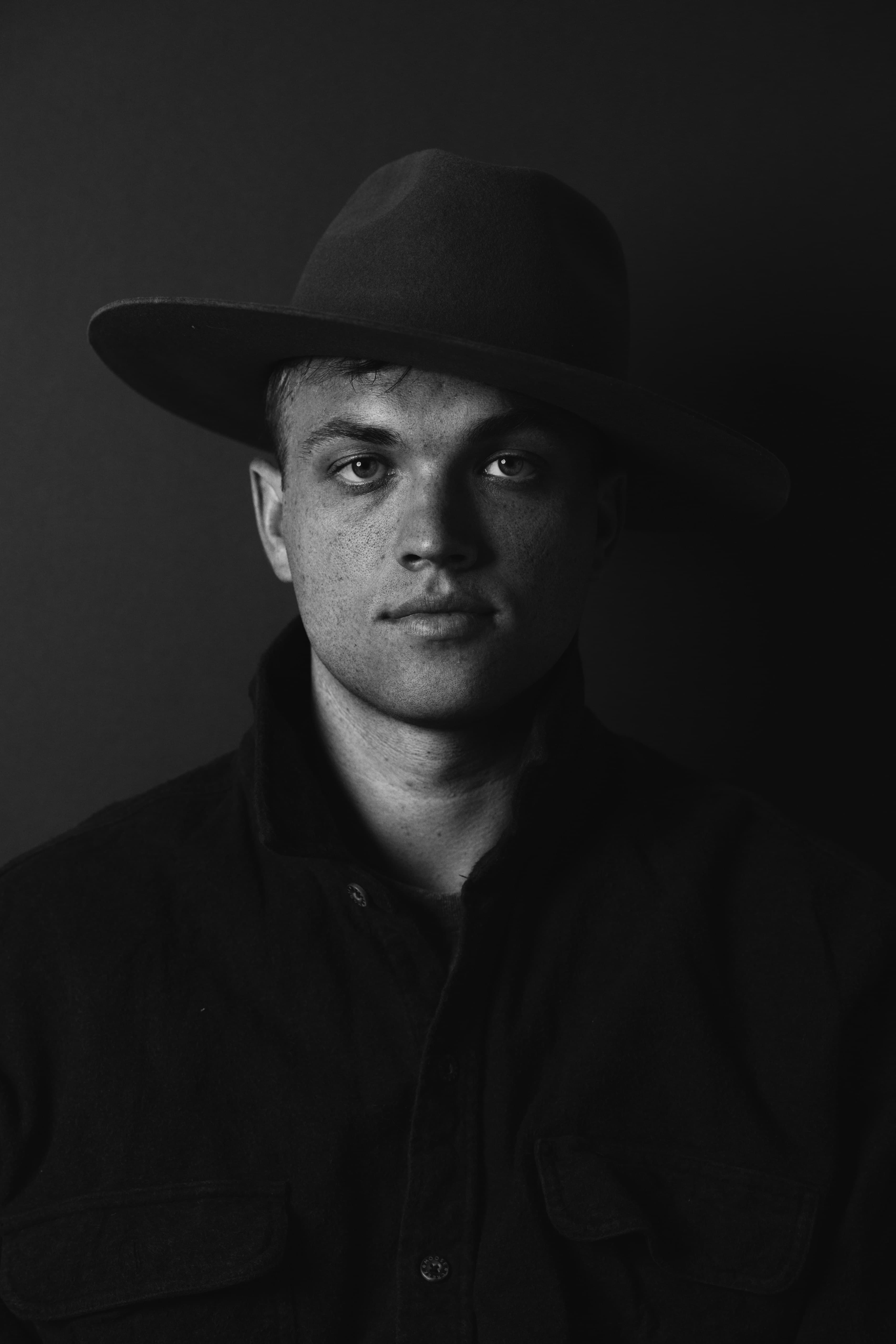 Black and white portrait of a man in a hat with dramatic lighting