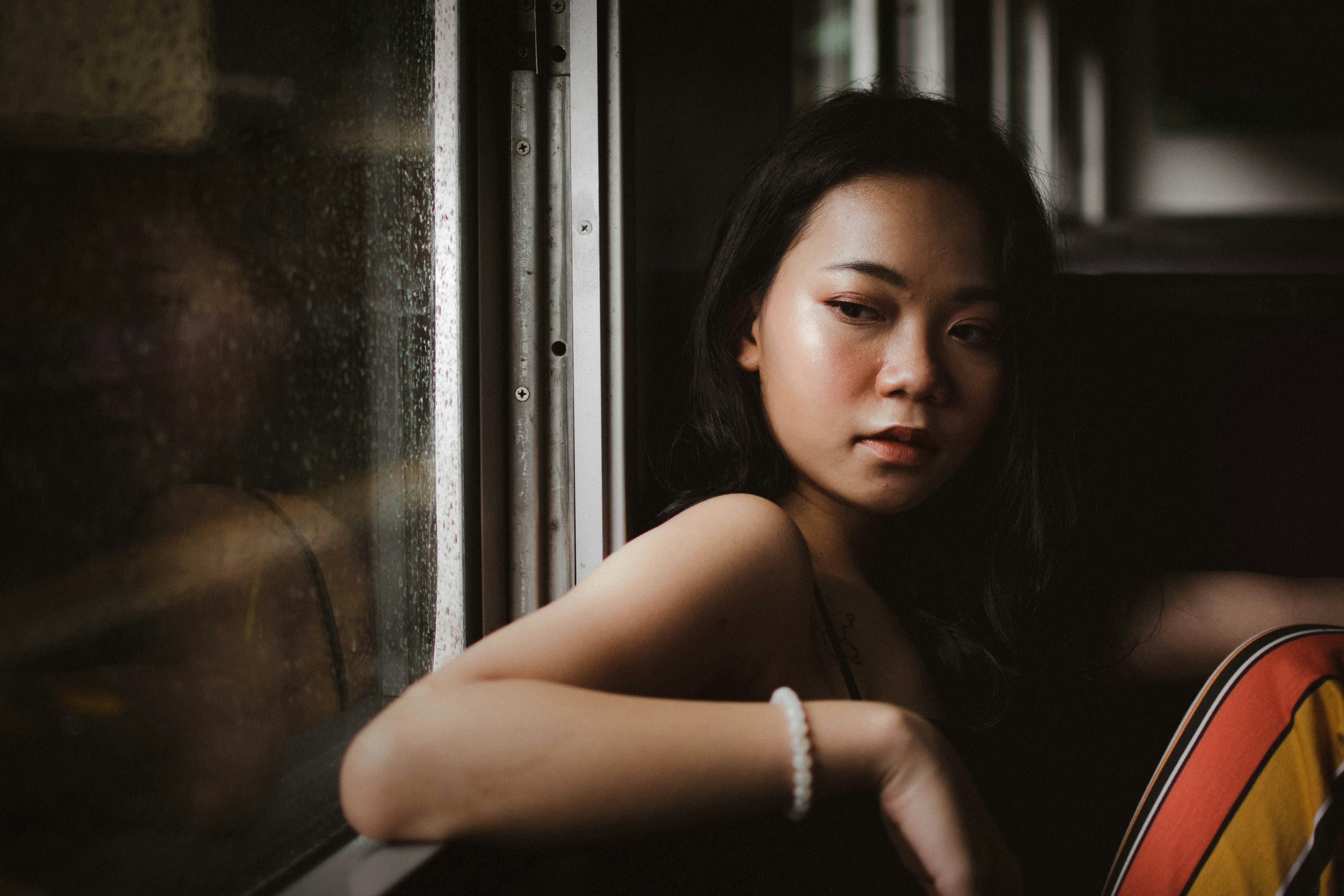 Woman with dark hair by a window in low light - perfect for spot metering